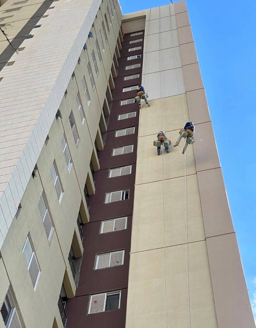 Equipe em plataforma de trabalho na fachada do edifício